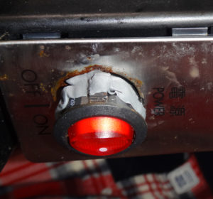 電源ボタンの隙間に不乾性パテを詰めて防水を強化している様子